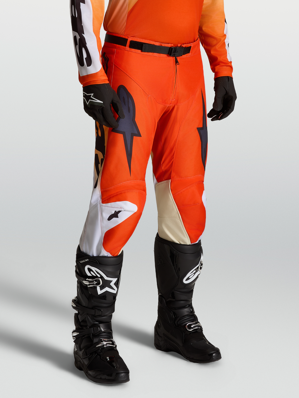 Alpinestars Racer Amber heren-motorcrossbroek, rood en zwart 600D polyweefsel, gedragen met Tech-laarzen en handschoenen.