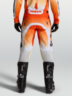Alpinestars Racer Amber broek, motocrossbroek in rood en wit, achteraanzicht op model met zwarte motorlaarzen.