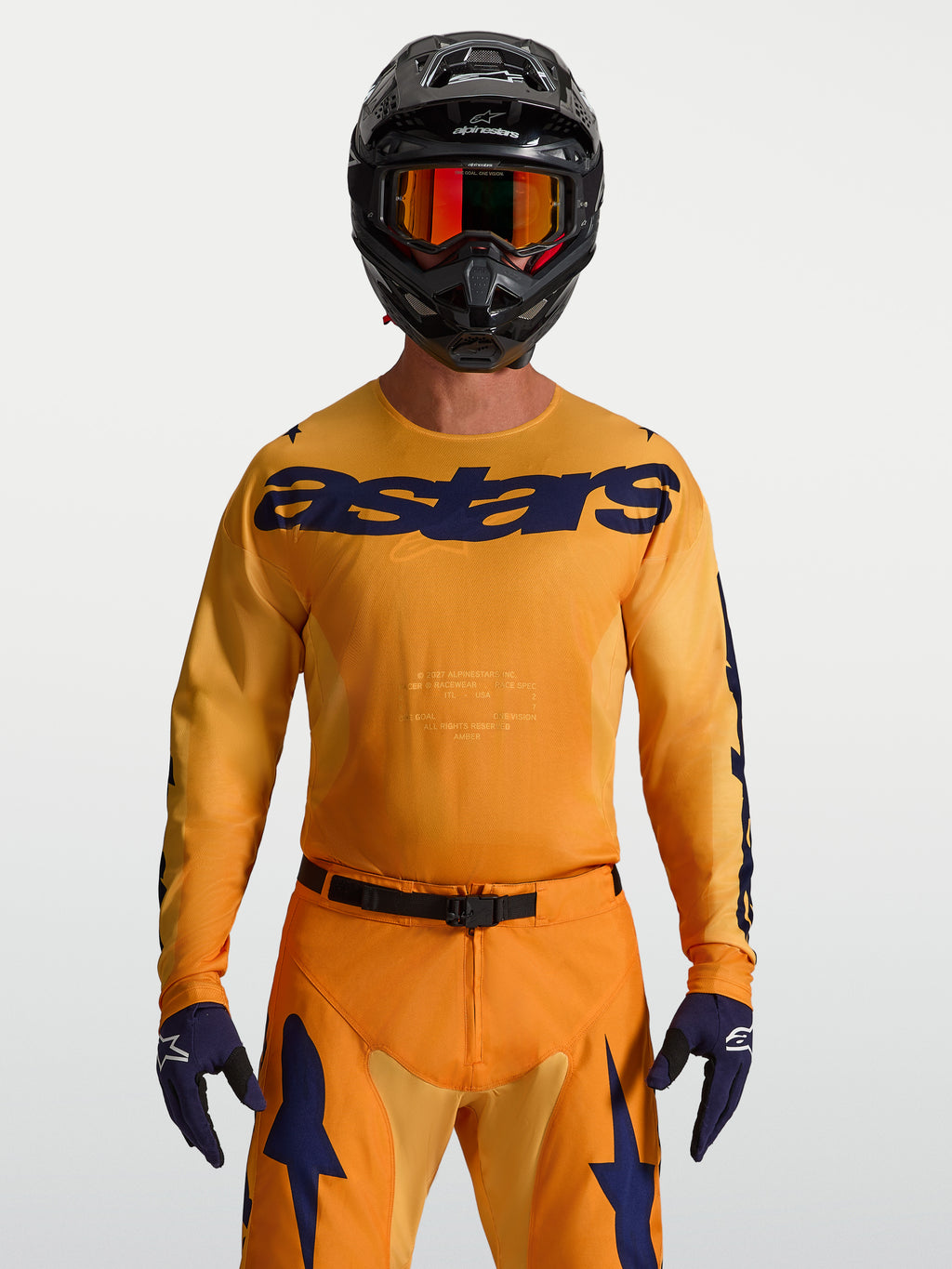 Alpinestars Racer Amber jersey, heren-motocrossjersey, oranje en diepblauw, vochtafvoerend polyfabric, model met zwarte helm.