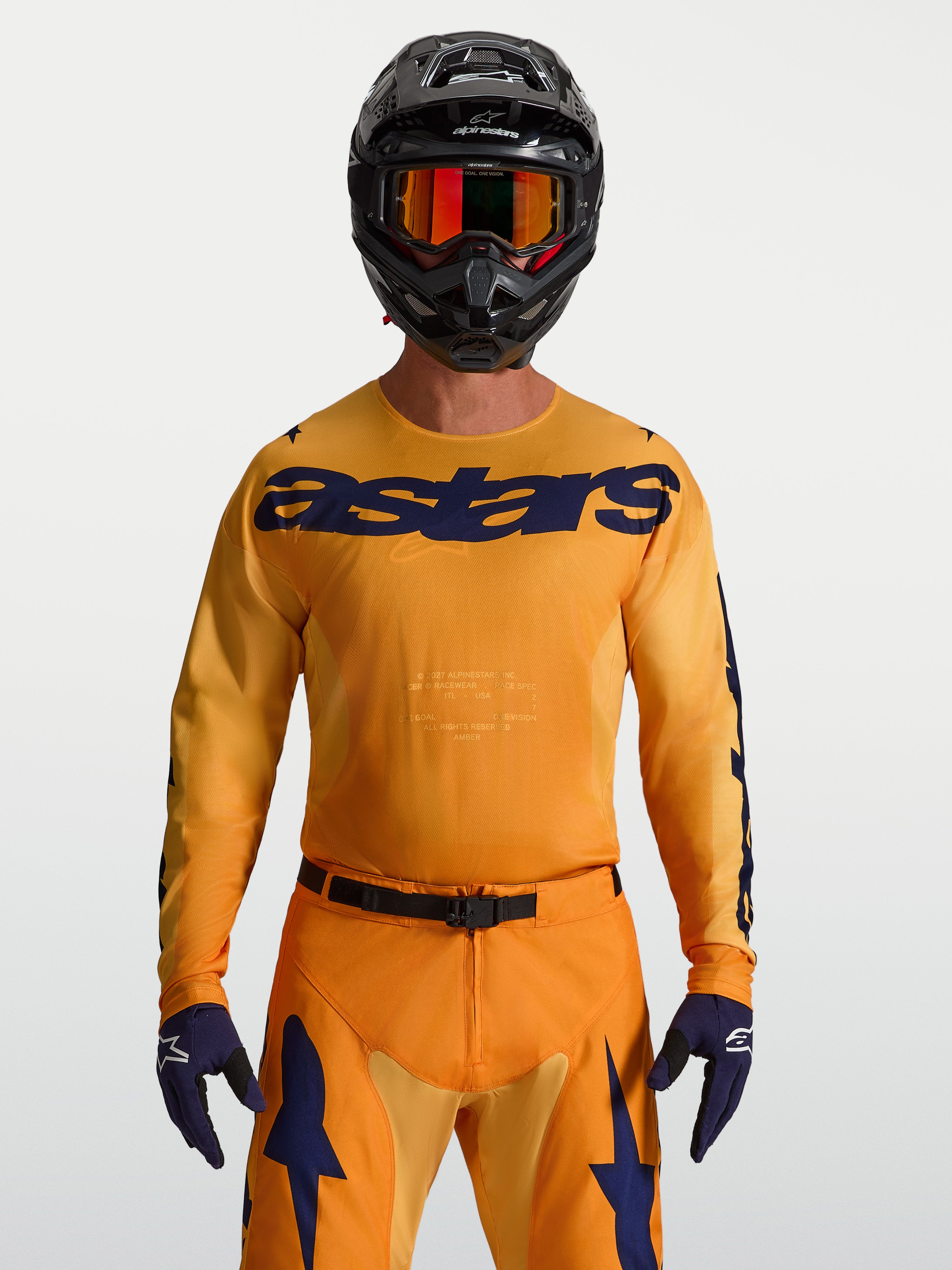 Alpinestars Racer Amber jersey, heren-motocrossjersey, oranje en diepblauw, vochtafvoerend polyfabric, model met zwarte helm.