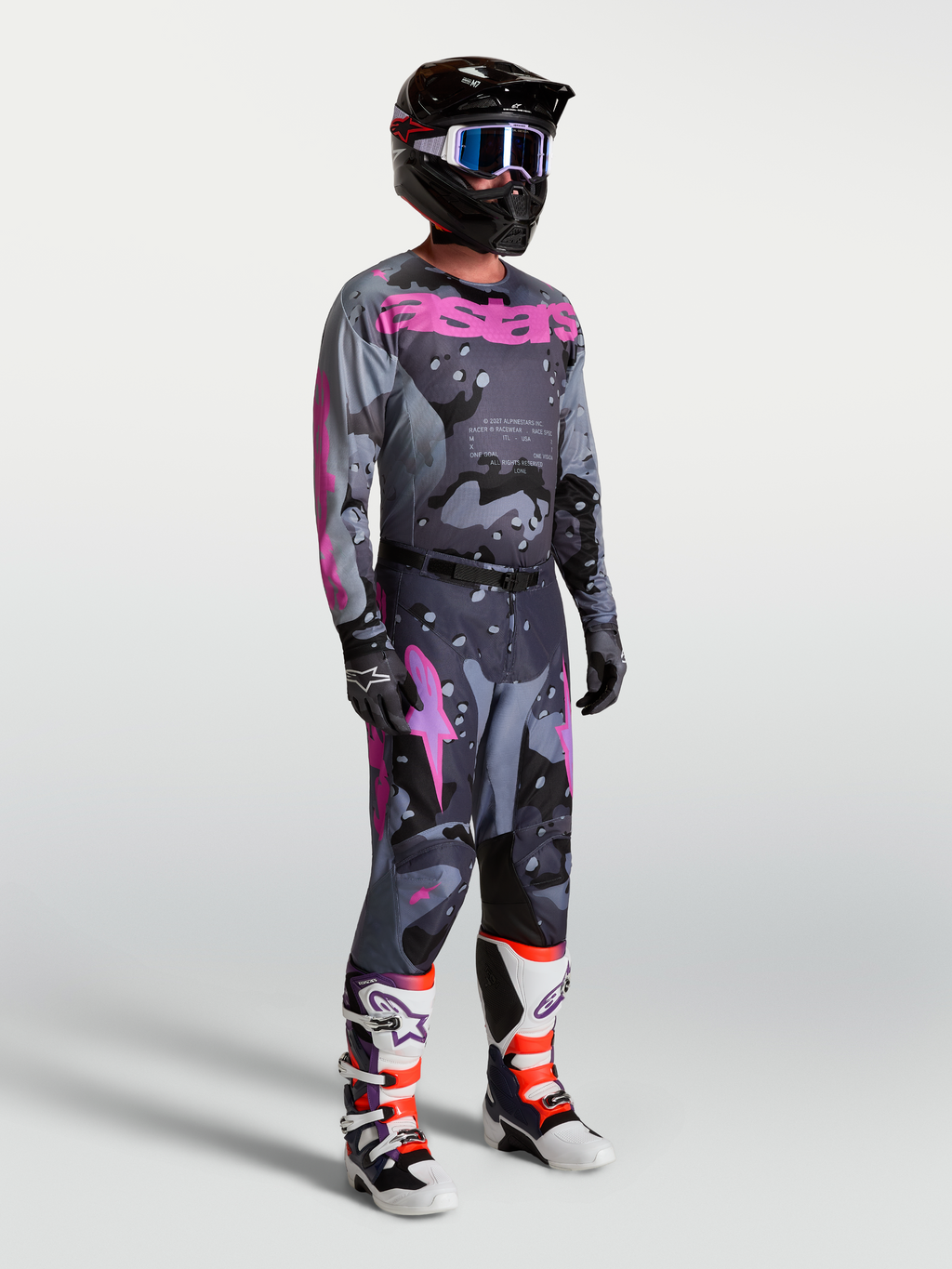 Alpinestars Racer Lone broek en jersey, heren motorcrossraceset in grijs camo en paars, gedragen door model met helm en laarzen voor een complete off-road look.