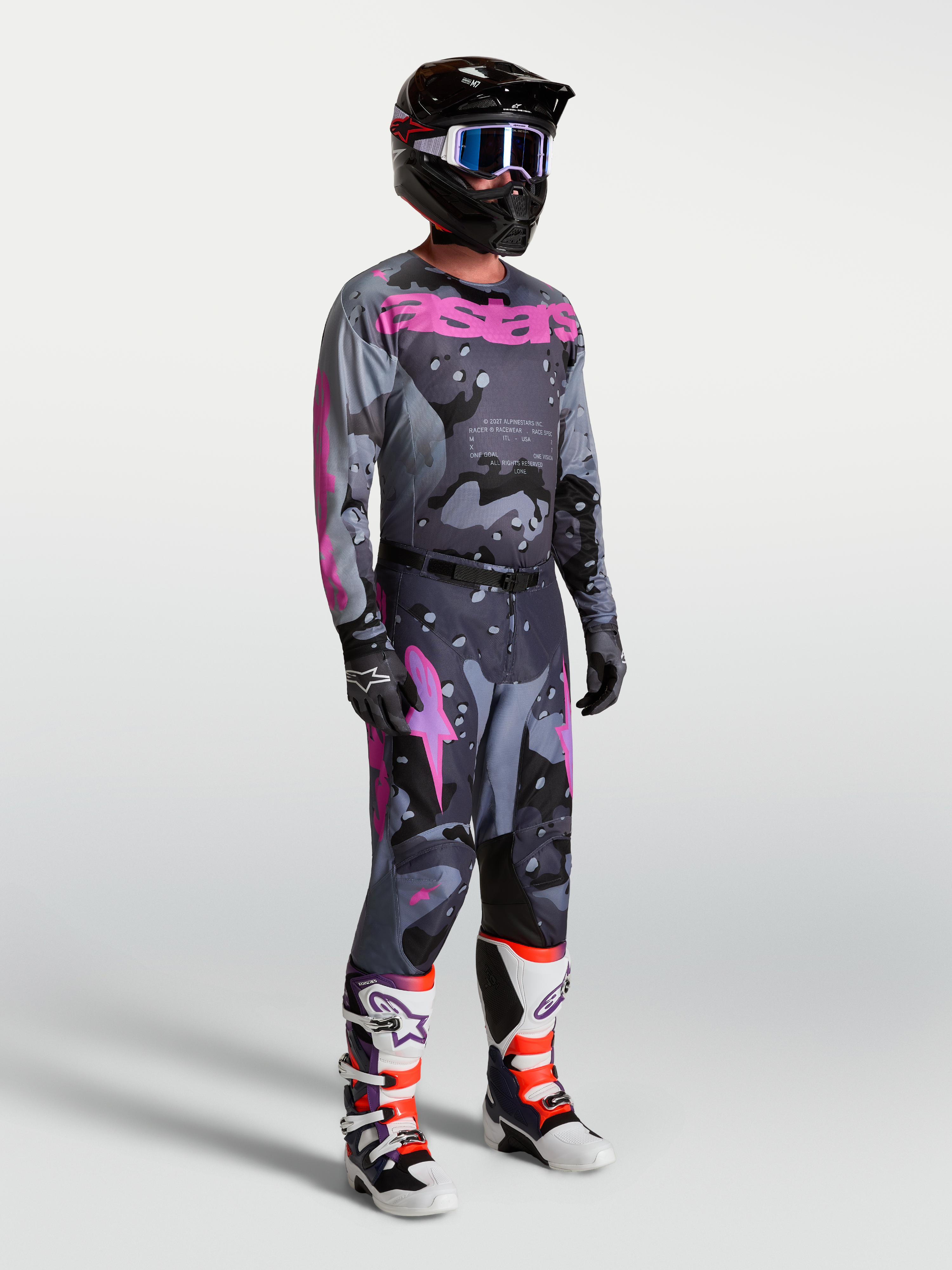 Alpinestars Racer Lone broek en jersey, heren motorcrossraceset in grijs camo en paars, gedragen door model met helm en laarzen voor een complete off-road look.