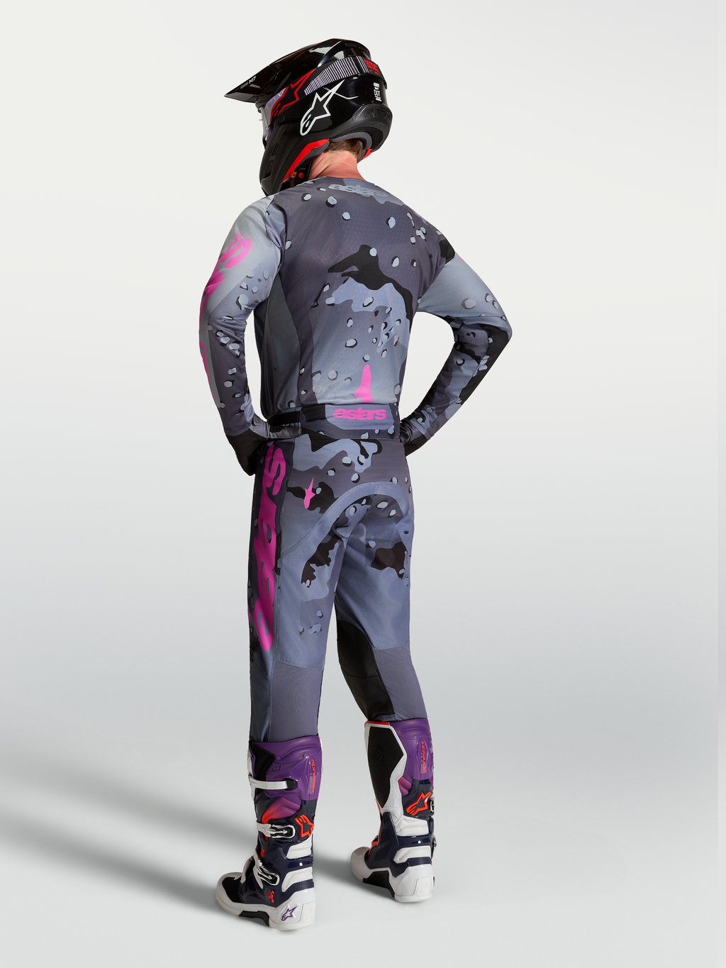 Alpinestars Racer Lone broek, motocrossbroek in grijs camo en paars, achteraanzicht met bijpassende jersey en motorlaarzen.