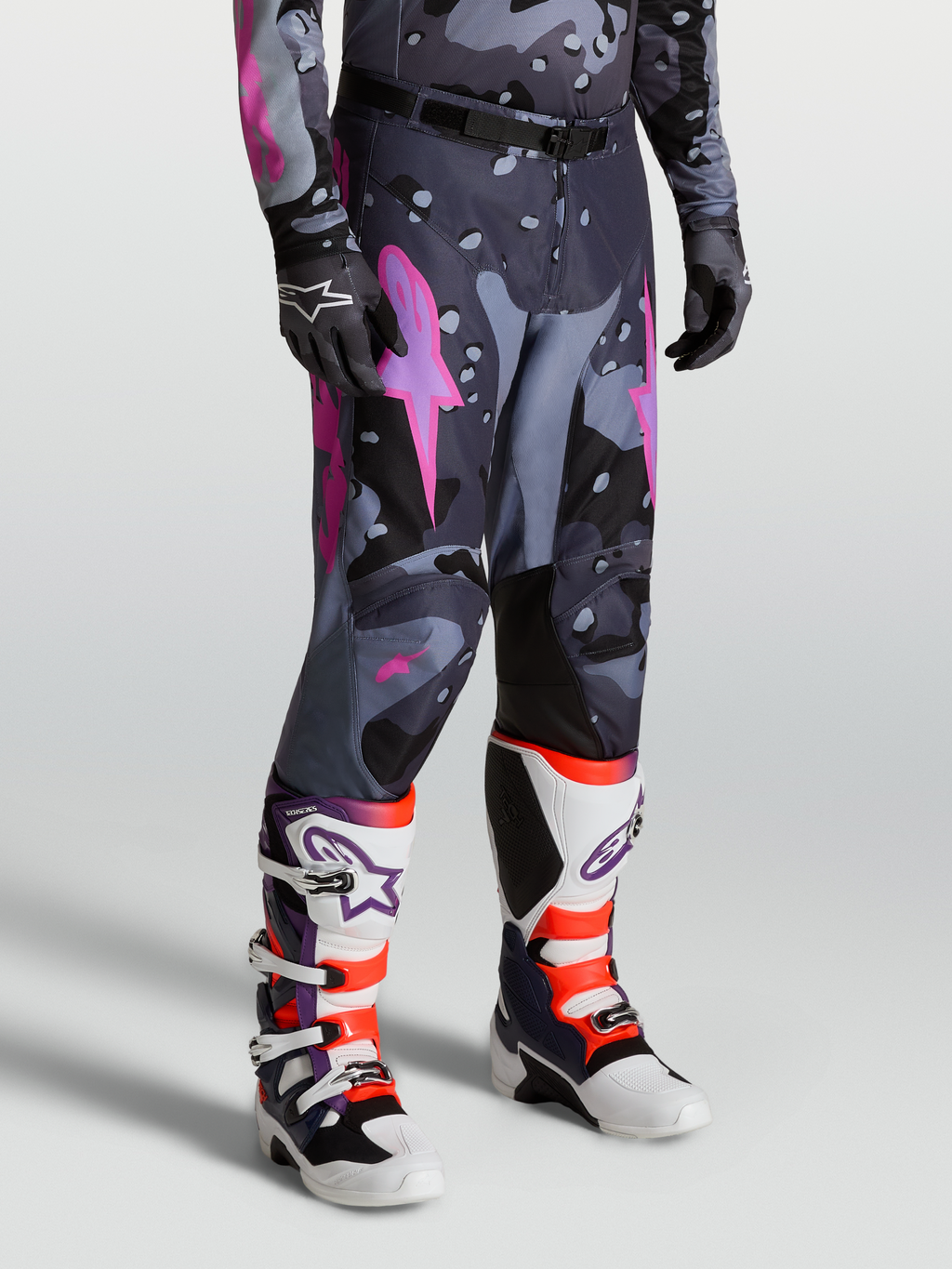 Alpinestars Racer Lone Broek, heren motorcrossbroek in grijs camo en paars, gedragen door model met laarzen, 600D polyweefsel en ergonomische stretch voor off-road prestaties.