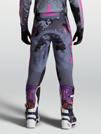 Alpinestars Racer Lone Broek, motorcrossbroek voor heren in grijs en paars camouflage, achteraanzicht op model met bijpassende MX-laarzen.