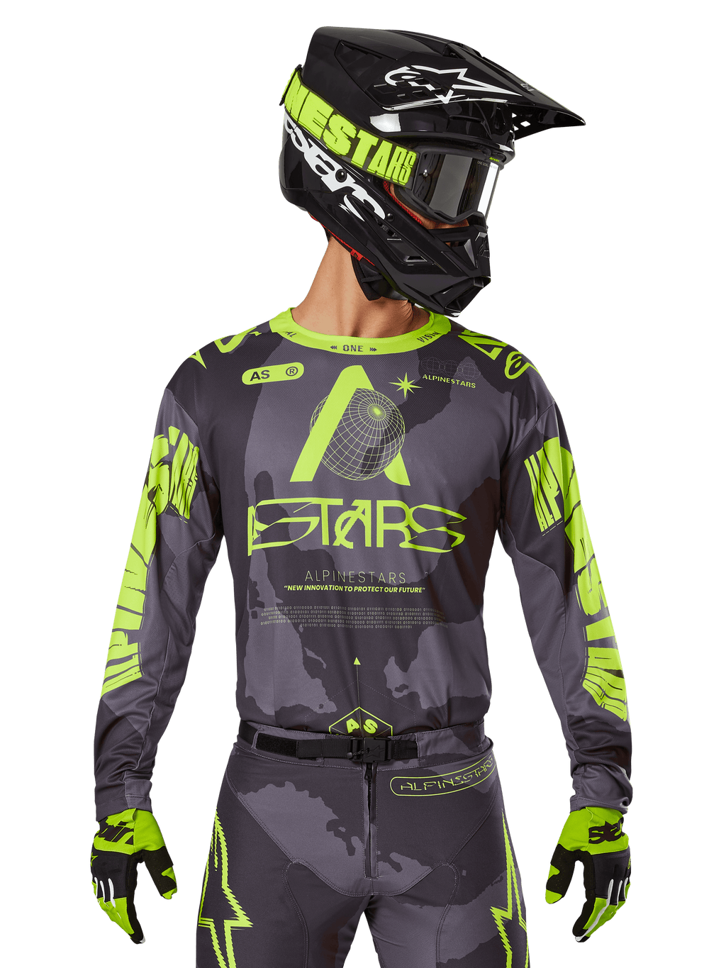 Alpinestars 2025 Racer Hollow Jersey, motorcross raceshirt, donkere camouflage en neongeel, gedragen met bijpassende broek, zwarte en gele helm met crossbril en zwarte handschoenen, voorzien van Alpinestars-branding en camouflage-ontwerp
