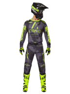 Motorcrossrijder in volledige race-uitrusting, Alpinestars 2025 Racer Hollow Jersey en bijpassende broek in Dark Camo Yellow Fluo, met opvallende fluorescerende gele graphics op een donkergrijze camouflage-achtergrond, gecombineerd met bijpassende handschoenen, felle fluogele laarzen en een zwarte helm.