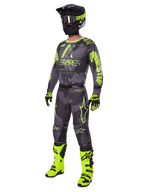 Motorcrossrijder in de Alpinestars 2025 Racer Hollow gearset, Dark Camo en Yellow Fluo jersey en broek, zwarte en fluorgele helm, bijpassende handschoenen en felgele fluo laarzen, gecoördineerde outfit voor off-road racing