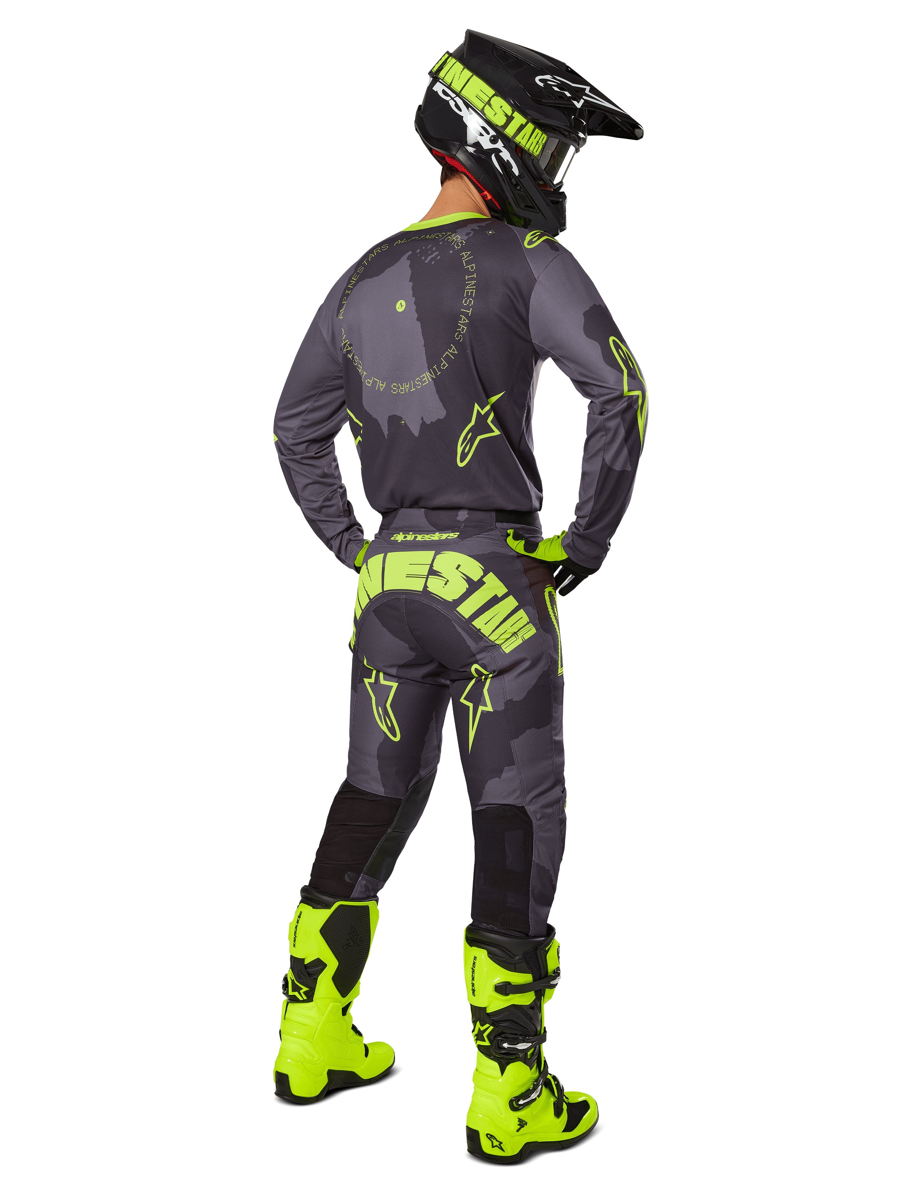 Rear view of a motocross rider wearing the 2025 Racer Hollow Gear Set in Dark Camo Yellow Fluo, featuring a gray camo jersey with yellow fluo accents, matching motocross pants with bold branding on the seat, bright yellow fluo boots, and a black helmet with yellow goggles.
