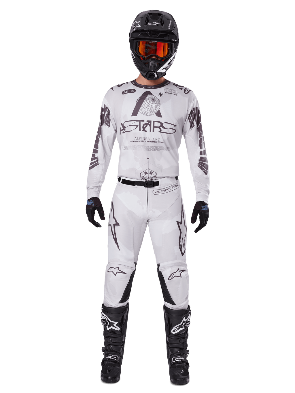 Alpinestars 2025 Racer Hollow Gear Set, wit met zwarte en grijze graphics, volledige motorcross race-outfit inclusief jersey en broek, gedragen met zwarte helm, oranje goggles, zwarte handschoenen en zwarte laarzen, hoogwaardige off-road kleding