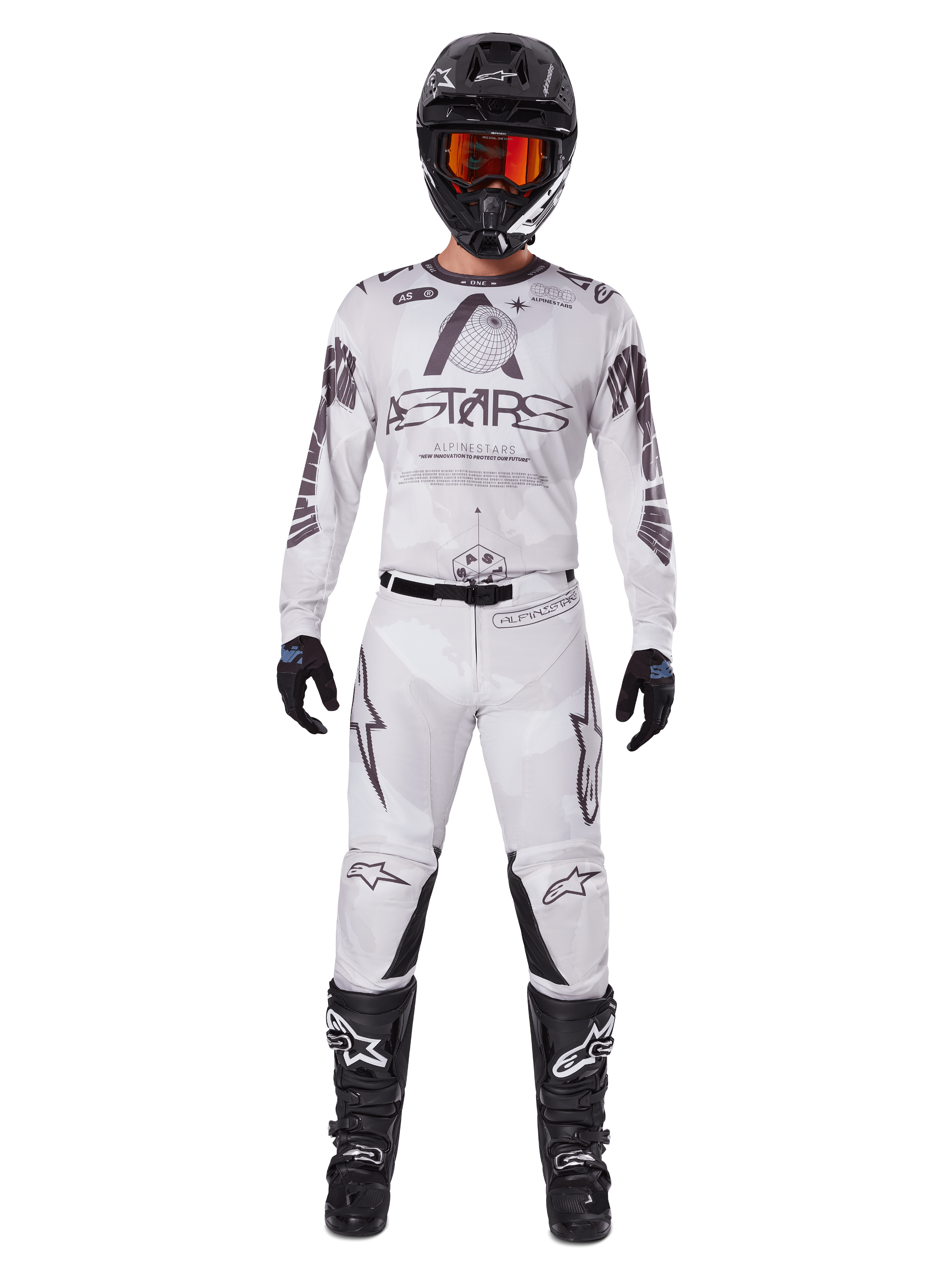 Alpinestars 2025 Racer Hollow Gear Set, wit met zwarte en grijze graphics, volledige motorcross race-outfit inclusief jersey en broek, gedragen met zwarte helm, oranje goggles, zwarte handschoenen en zwarte laarzen, hoogwaardige off-road kleding