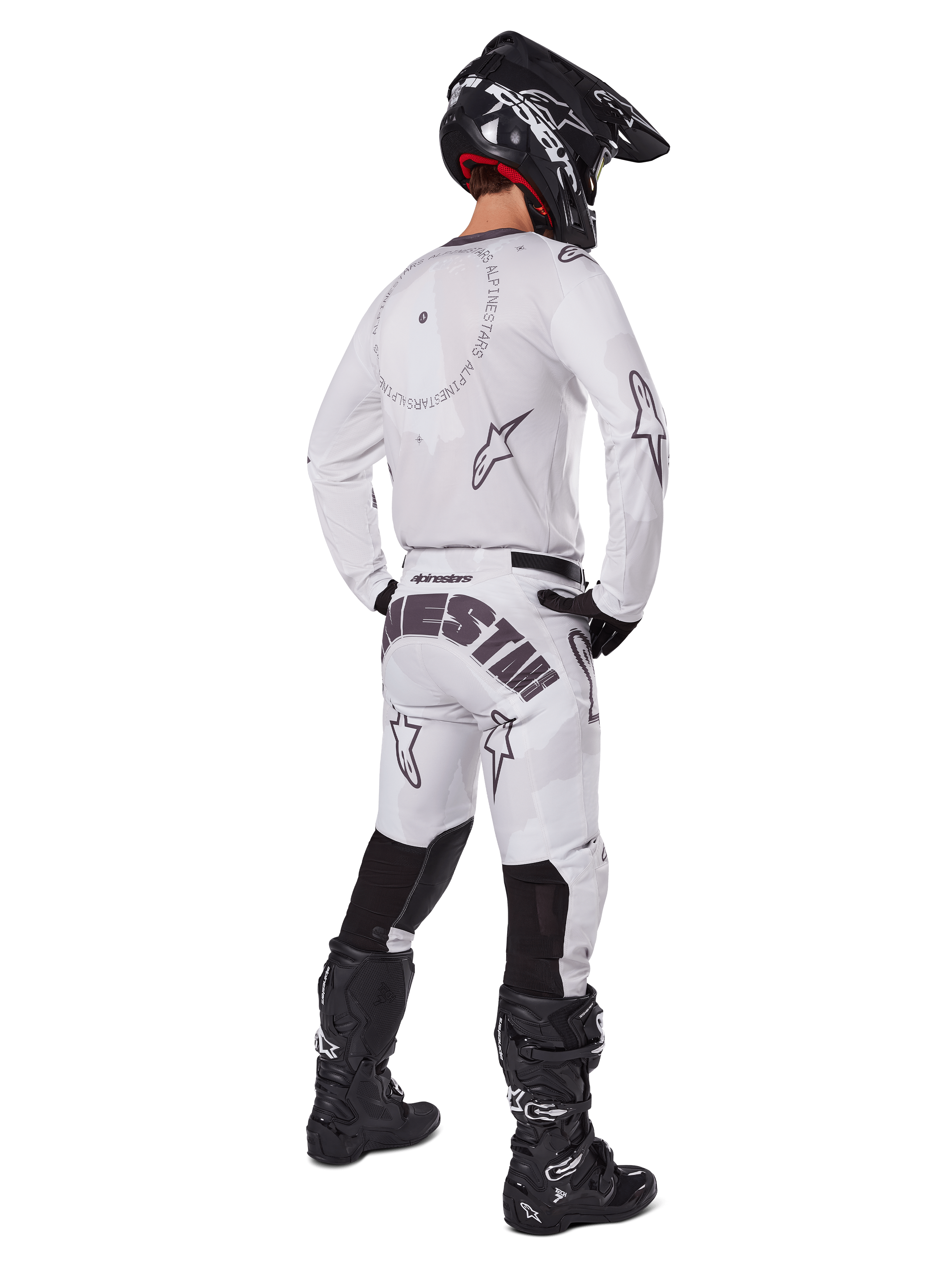 Alpinestars 2025 Racer Hollow Gear Set, wit, achteraanzicht van een motorcrosser met wit shirt en broek, zwarte logo's, zwarte helm en zwarte laarzen, professionele off-road race-outfit