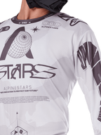 Close-up van Alpinestars 2025 Racer Hollow Jersey, wit en grijs, met zwarte grafische prints, wereldbol-logo en binaire code, technische motocrosskleding voor off-road rijden