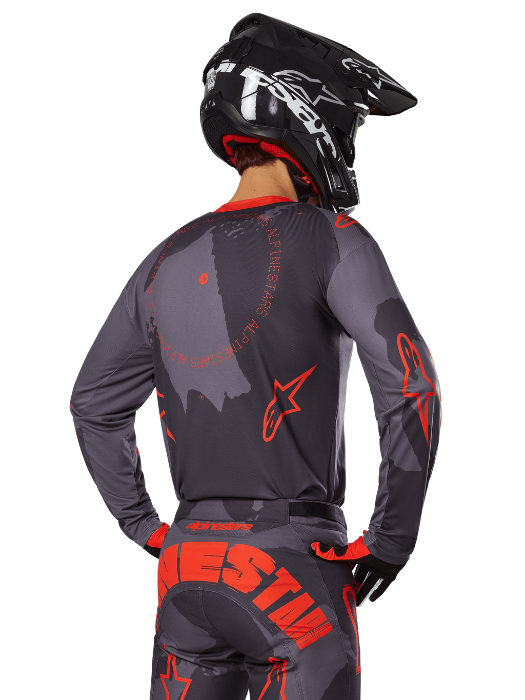 Motocrossrijder van achteren gezien in volledige race-uitrusting, Gray Camo jersey met Orange Fluo accenten en ronde branding op de rug, bijpassende camouflagebroek met grote oranje Alpinestars-tekst op het zitvlak, zwarte helm en oranje met zwarte handschoenen, gecoördineerde outfit voor off-road racen