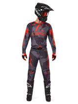Alpinestars 2025 Racer Hollow Jersey en bijpassende broek in Gray Camo Orange Fluo, complete motorcross outfit met zwarte helm, bril, handschoenen en laarzen, voorzien van opvallende oranje logo's en camouflagepatroon