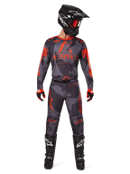 Alpinestars 2025 Racer Hollow Gear Set, motorcrosser in Gray Camo jersey en broek met Orange Fluo accenten, zwarte helm met oranje bril, rood-zwarte handschoenen, zwarte laarzen met witte logo's, volledige race-outfit voor off-road