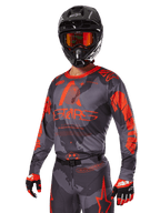 Alpinestars 2025 Racer Hollow Gear Set in rood, motorcross outfit met een grijs en zwart camouflagepatroon en opvallende rode branding, compleet met jersey, broek, handschoenen en een zwarte helm met rode bril