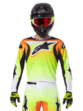 Alpinestars 2025 Fluid Wurx Jersey, motorcross jersey, neongeel, oranje en wit, gedragen met bijpassende broek en zwarte helm met rode bril, complete MX-uitrusting op de rijder