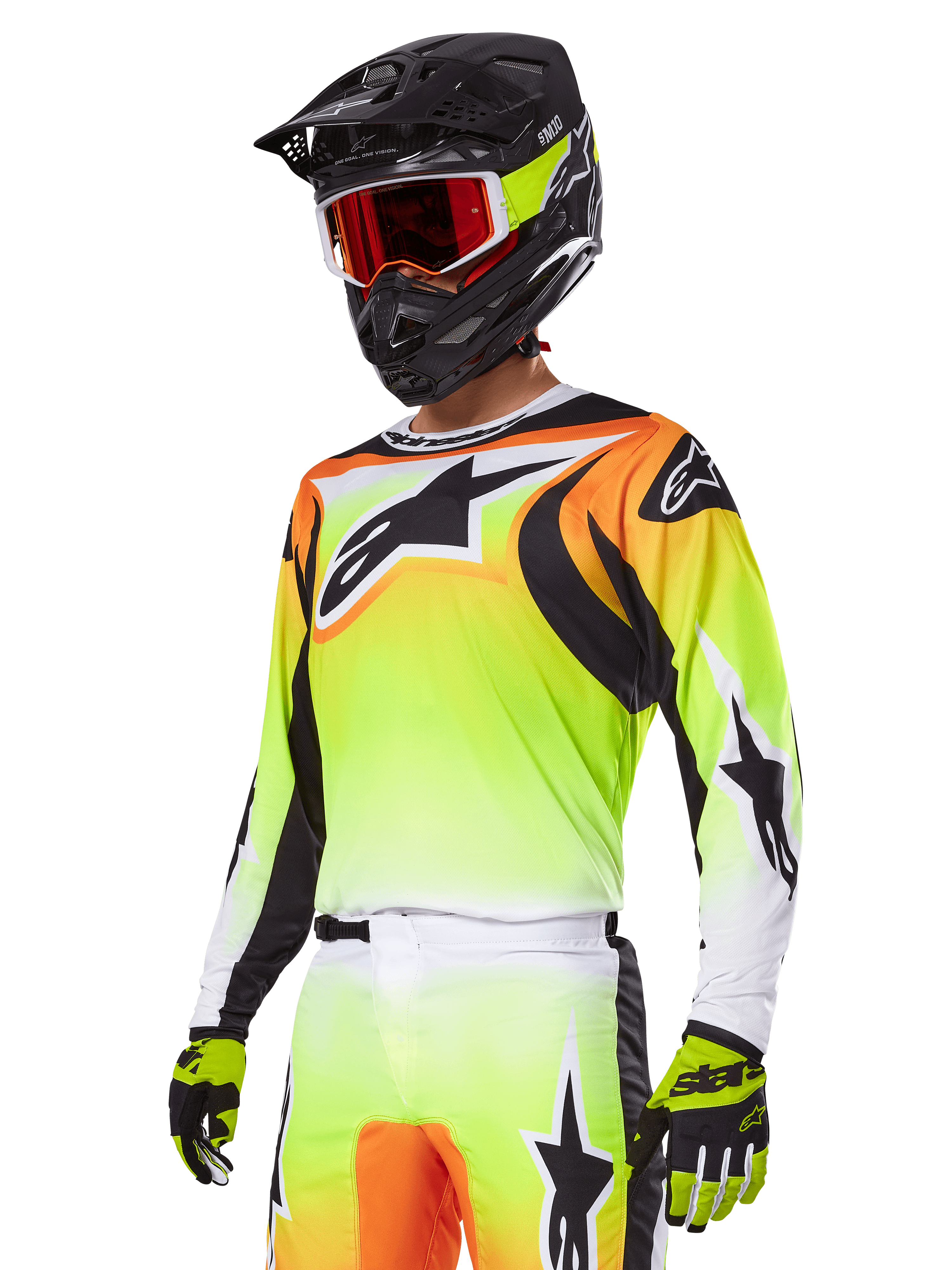 Motocross-rijder in Alpinestars 2025 Fluid Wurx Gear Set, jersey met geel en oranje kleurverloop, zwarte accenten en grote sterlogo's, bijpassende motorcrossbroek, zwarte full-face helm met rood getinte bril en gele handschoenen, gecoördineerde high-performance outfit voor off-road racen