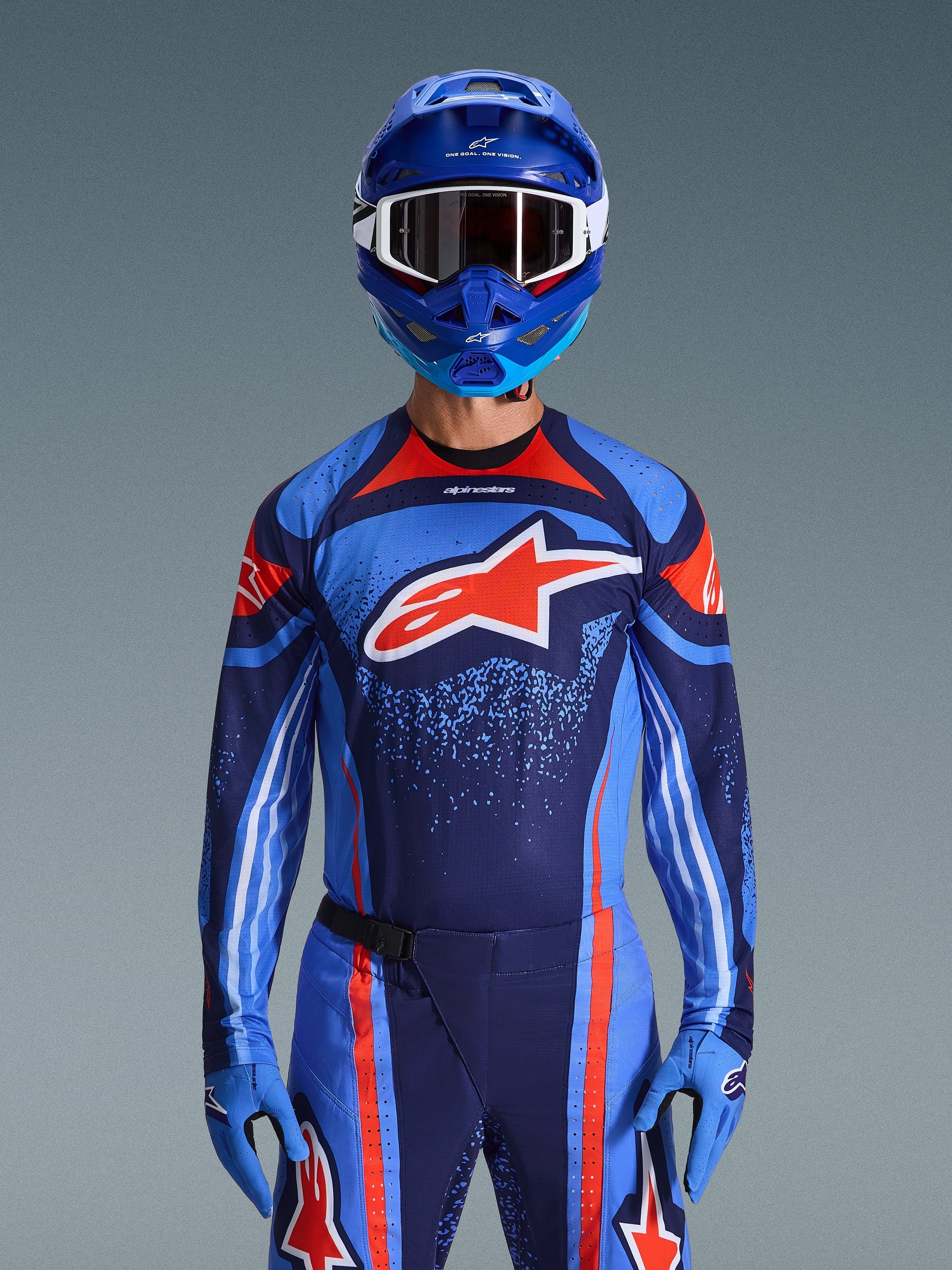 Alpinestars 2026 Techstar Nomur Jersey, motocrosser in Dark Navy, oranje en UCLA Blue, bijpassende broek en blauwe handschoenen, blauwe helm met witte crossbril, groot rood en wit Alpinestars-logo op de borst, gecoördineerde uitrusting voor off-road racing