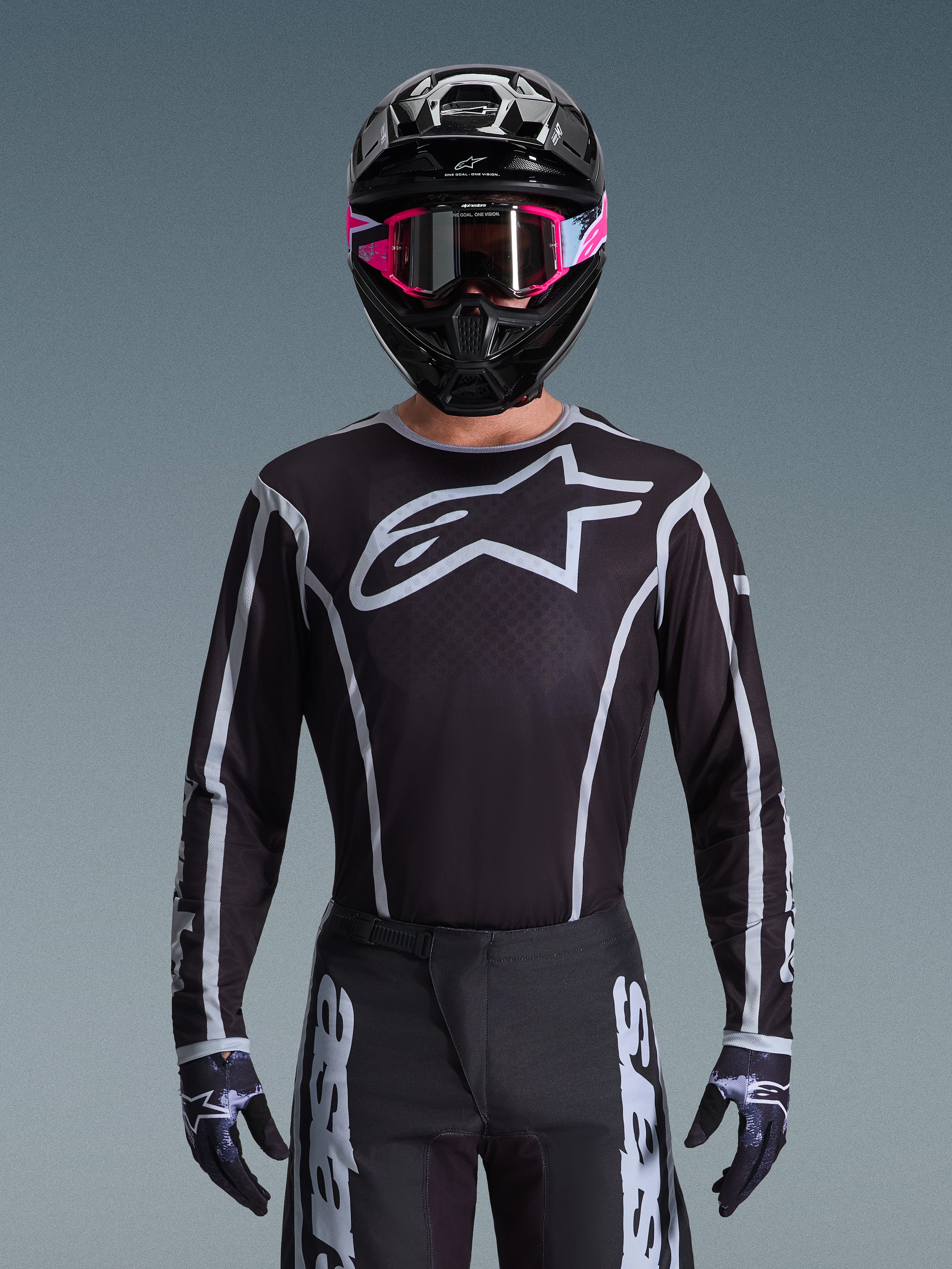 Alpinestars 2026 Fluid Apex Gear Set, Motocross jersey and pants in black and white, features large chest logo and geometric line designs, worn with a black helmet and pink goggles, performance gear for off-road motocross racing.