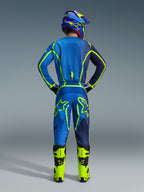Alpinestars 2026 Fluid Apex Gear Set, back view of a motocross rider wearing a blue and navy jersey and matching pants with vibrant neon green accents, neon yellow boots, and a purple helmet, professional off-road racing outfit.