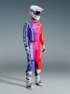 Motocross rider wearing complete racing gear, 2026 Fluid Apex Jersey and Pants with a vibrant purple, pink, and orange gradient, white helmet with blue goggles, white and black boots, and white gloves, coordinated outfit for off-road motocross.