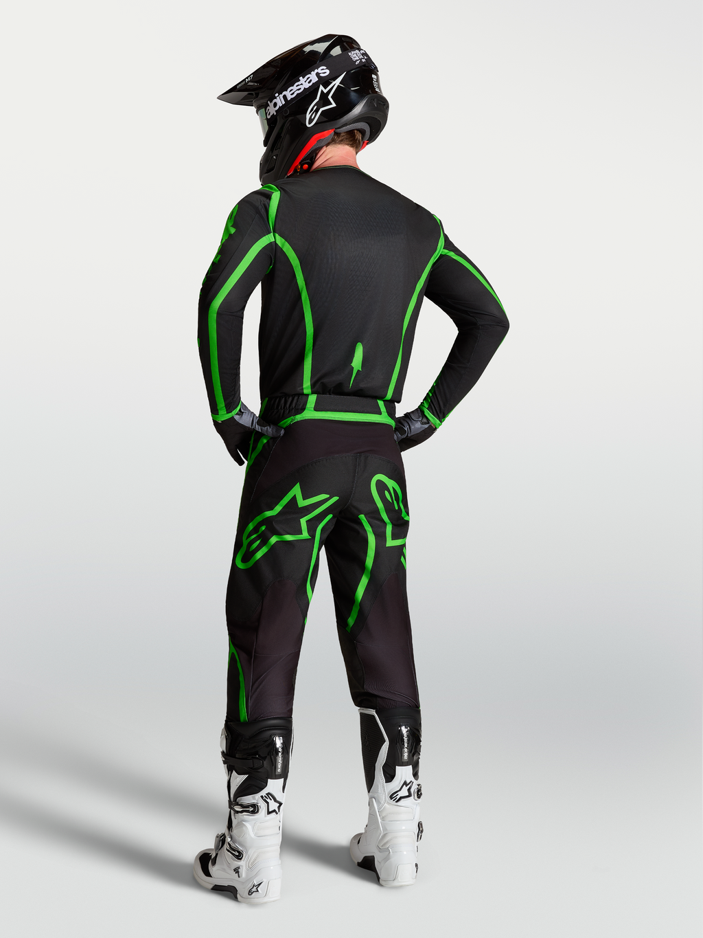 Alpinestars Fluid Apex V2 broek, heren motocrossbroek, zwart en fluogroen, ergonomische pasvorm, getoond op model van achteren in een volledige race-uitrusting.