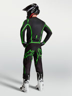 Alpinestars Fluid Apex V2 broek, heren motocrossbroek, zwart en fluogroen, ergonomische pasvorm, getoond op model van achteren in een volledige race-uitrusting.
