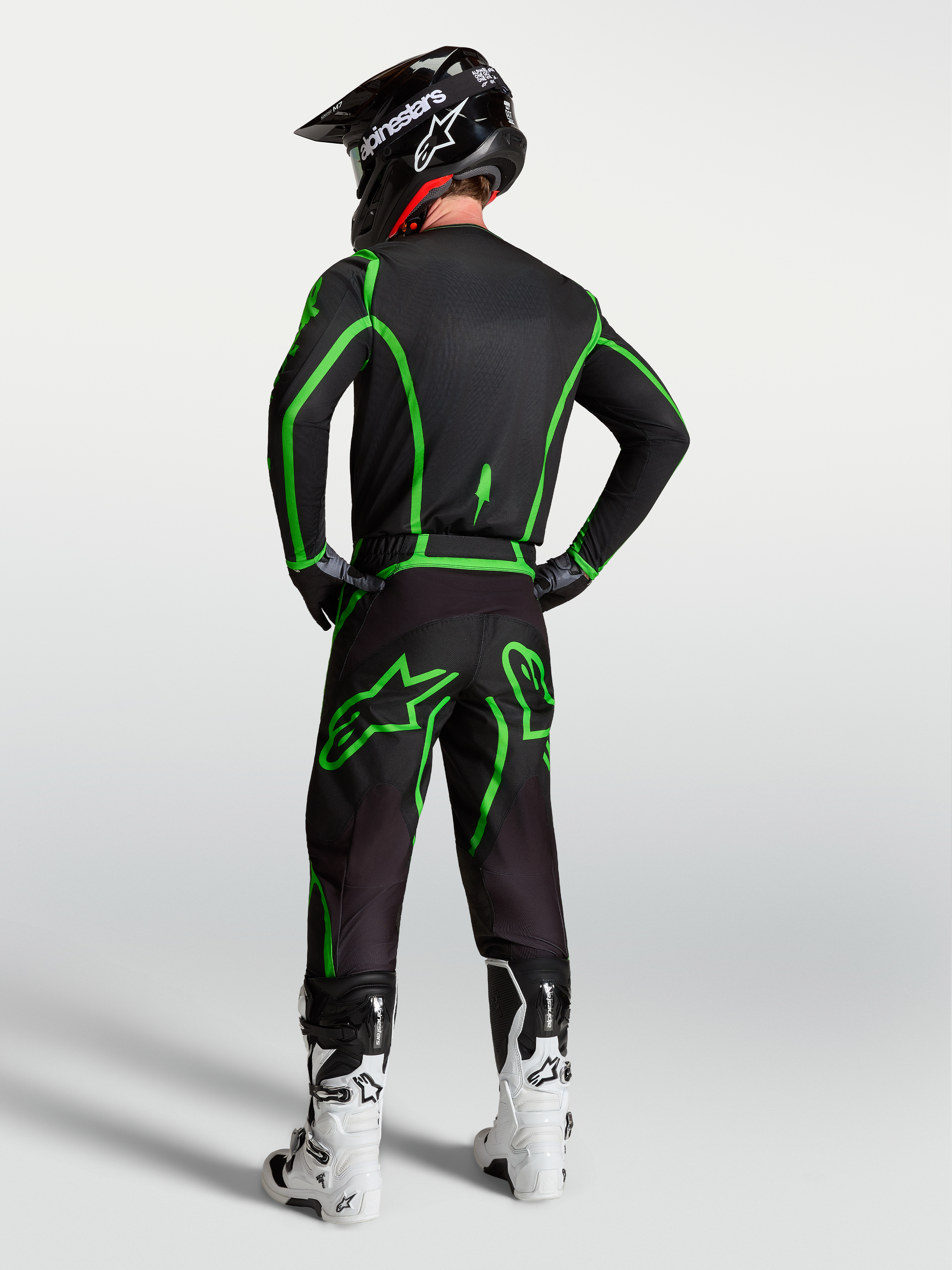Alpinestars Fluid Apex V2 broek, heren motocrossbroek, zwart en fluogroen, ergonomische pasvorm, getoond op model van achteren in een volledige race-uitrusting.