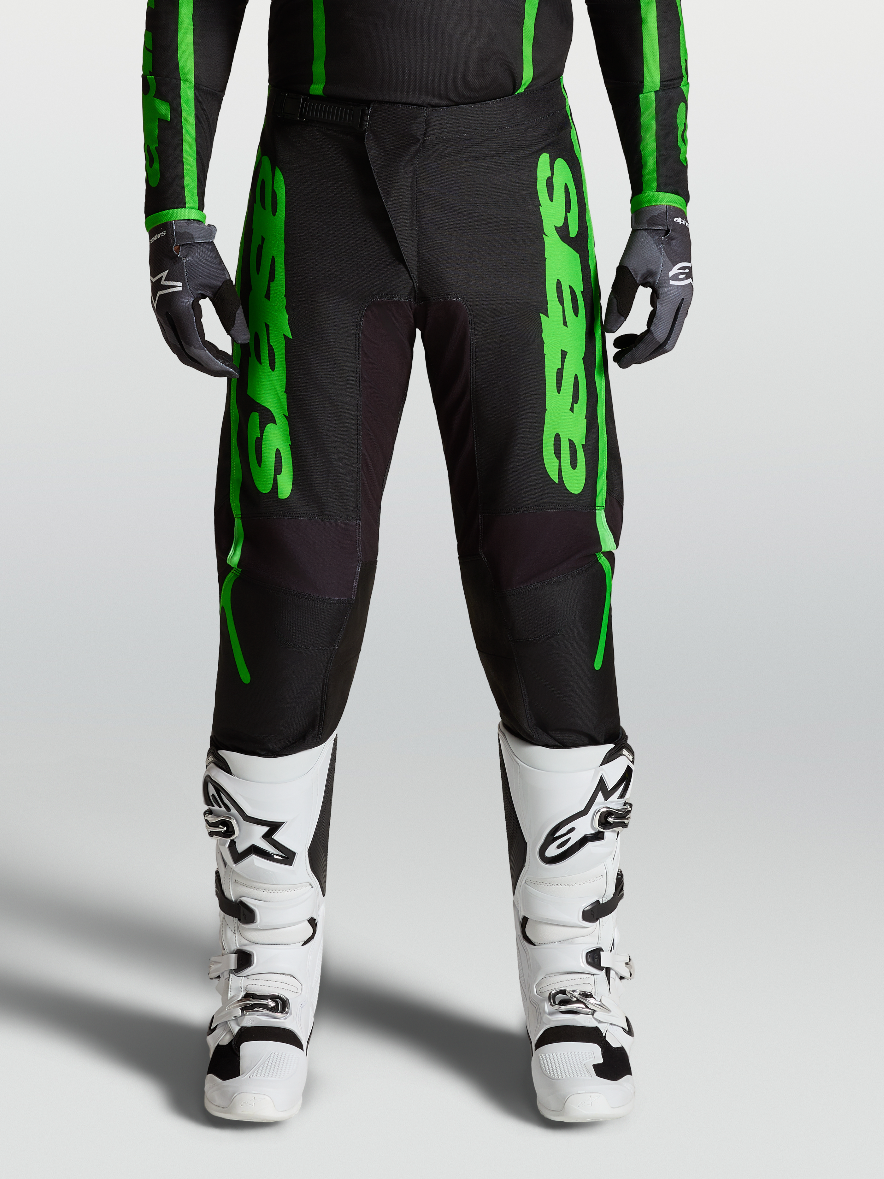 Alpinestars Fluid Apex V2 broek 2027, heren motocrossbroek, groen en zwart, verstevigde knieën, witte motorlaarzen.