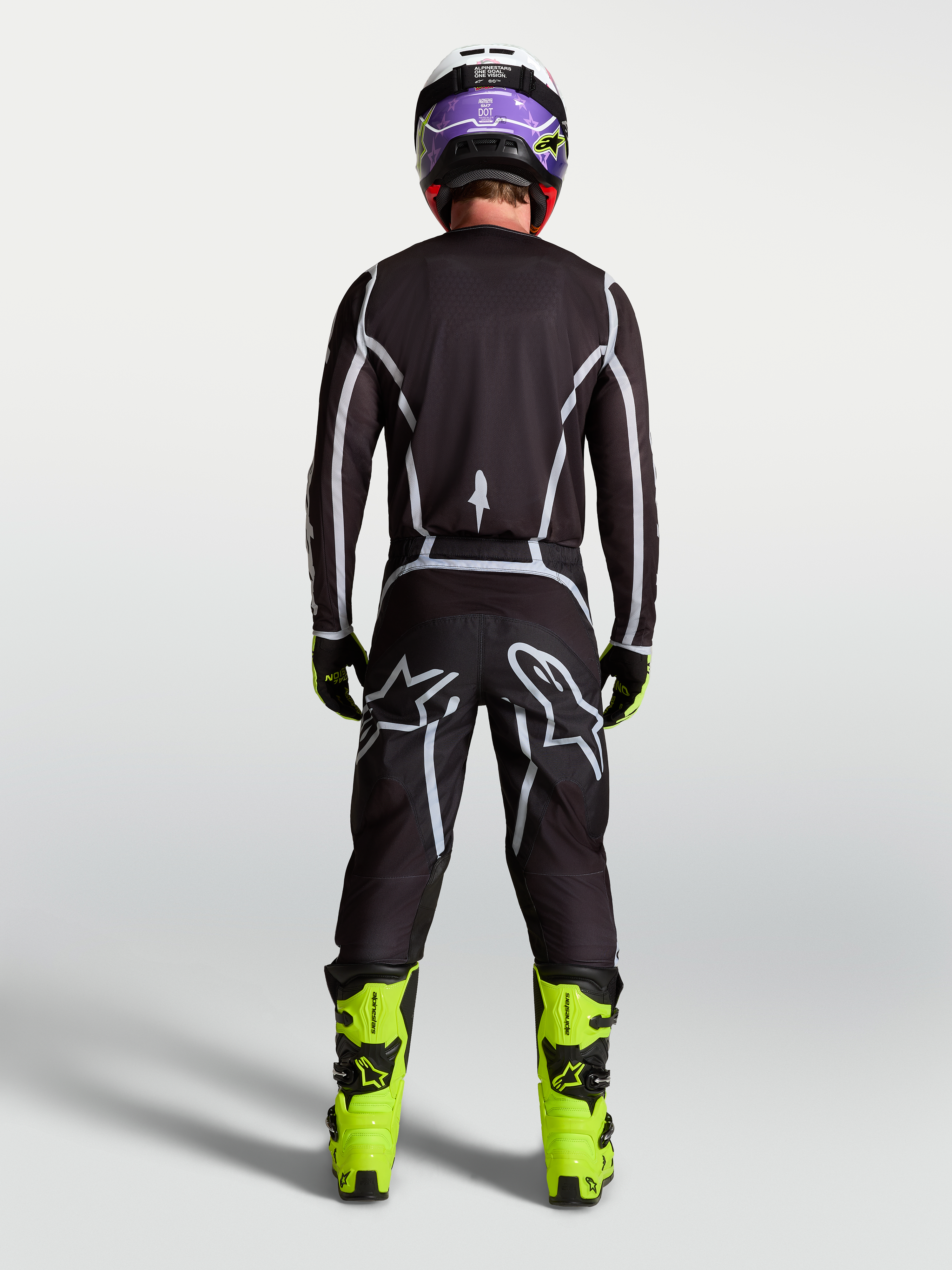 Alpinestars Fluid Apex V2 jersey, heren-motorcrosskleding, zwart en zilver, achteraanzicht op rijder in race-uitrusting.
