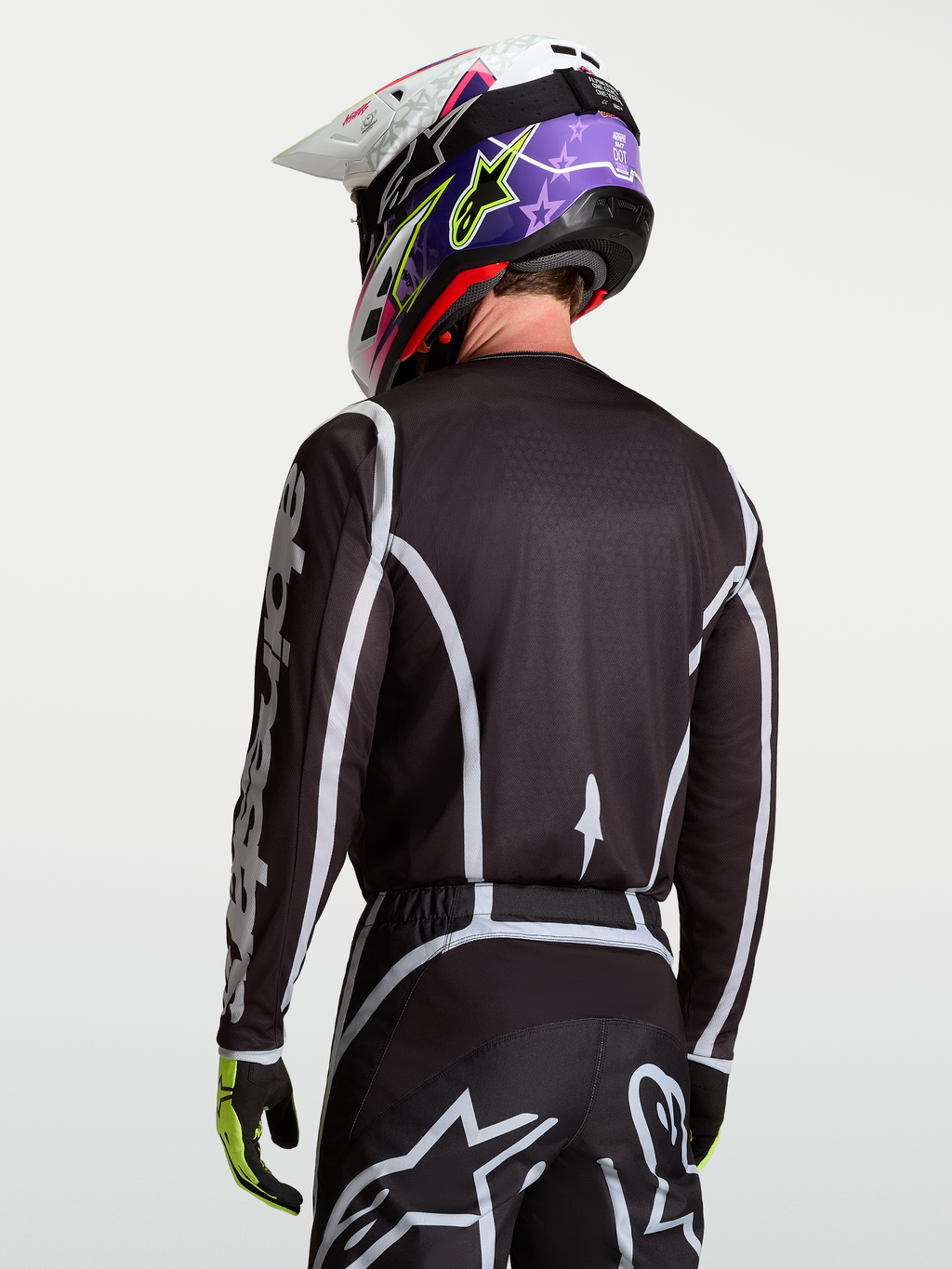Alpinestars Fluid Apex V2 Jersey, zwart en zilver motocross shirt op model van achteren gezien, vochtafvoerend polyfabric en ergonomische snit.