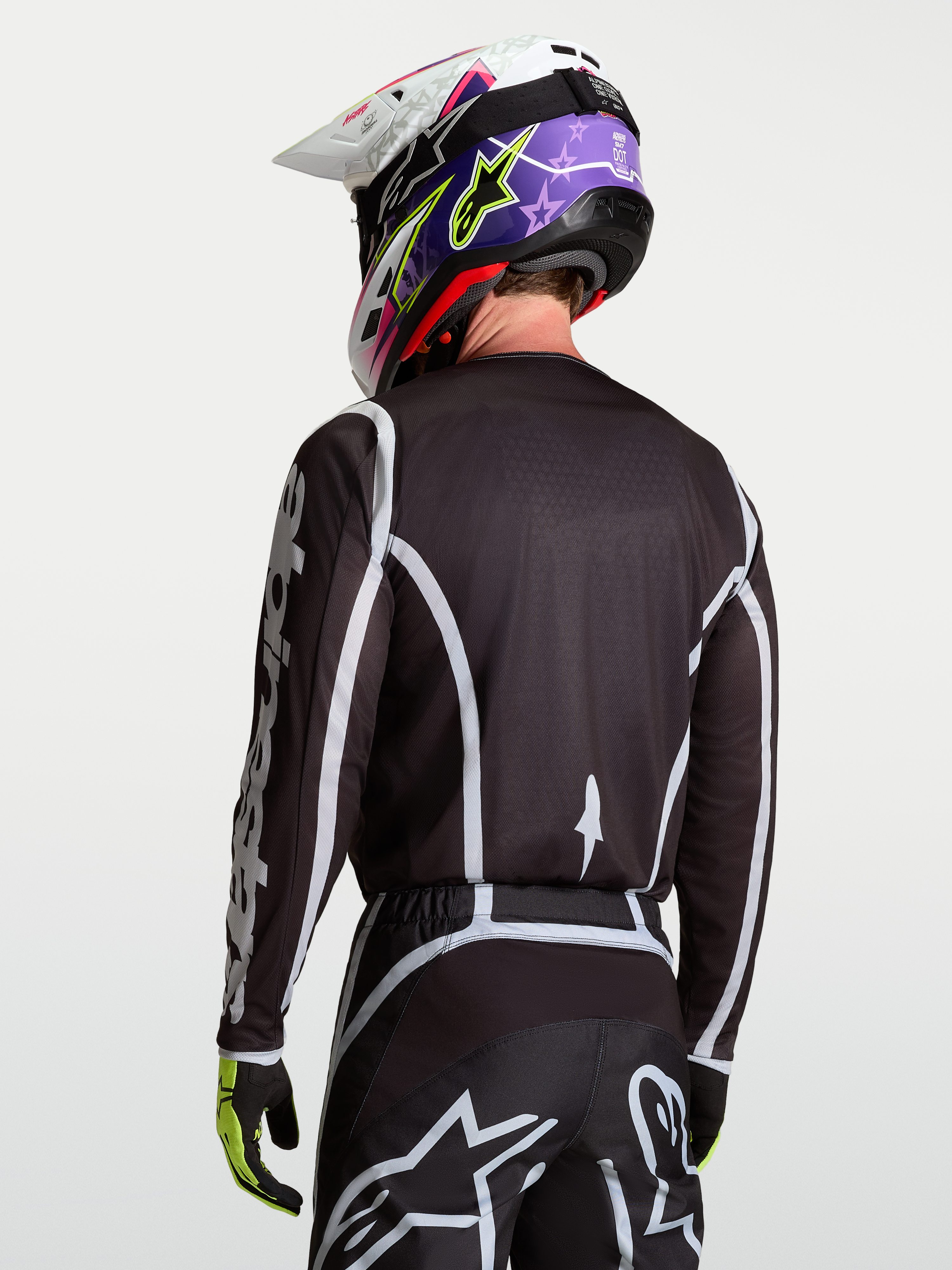 Alpinestars Fluid Apex V2 Jersey, zwart en zilver motocross shirt op model van achteren gezien, vochtafvoerend polyfabric en ergonomische snit.