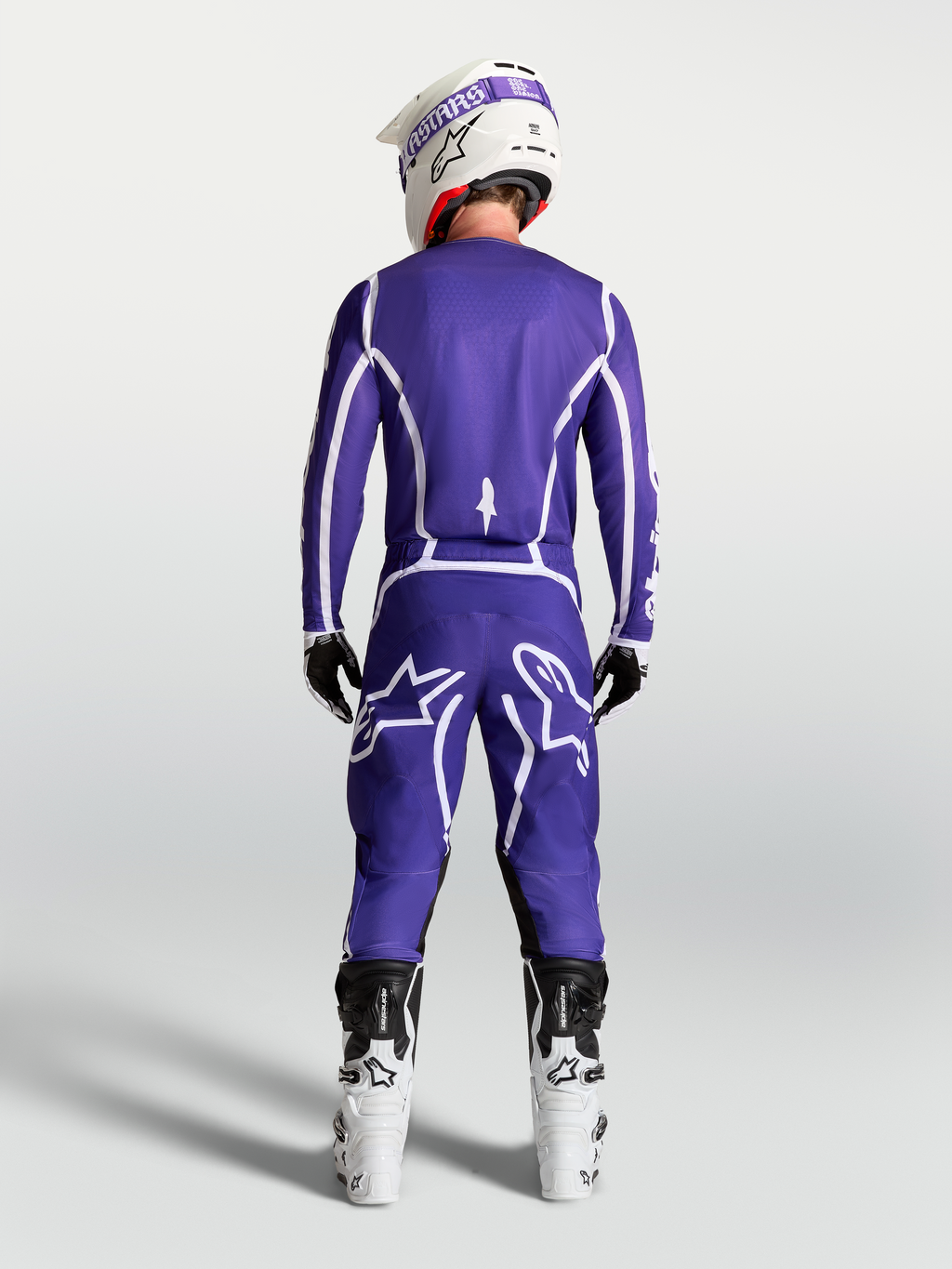 Alpinestars Fluid Apex V2 jersey, blauw en wit, achteraanzicht van motorcrosser met bijpassende broek en witte motorlaarzen.