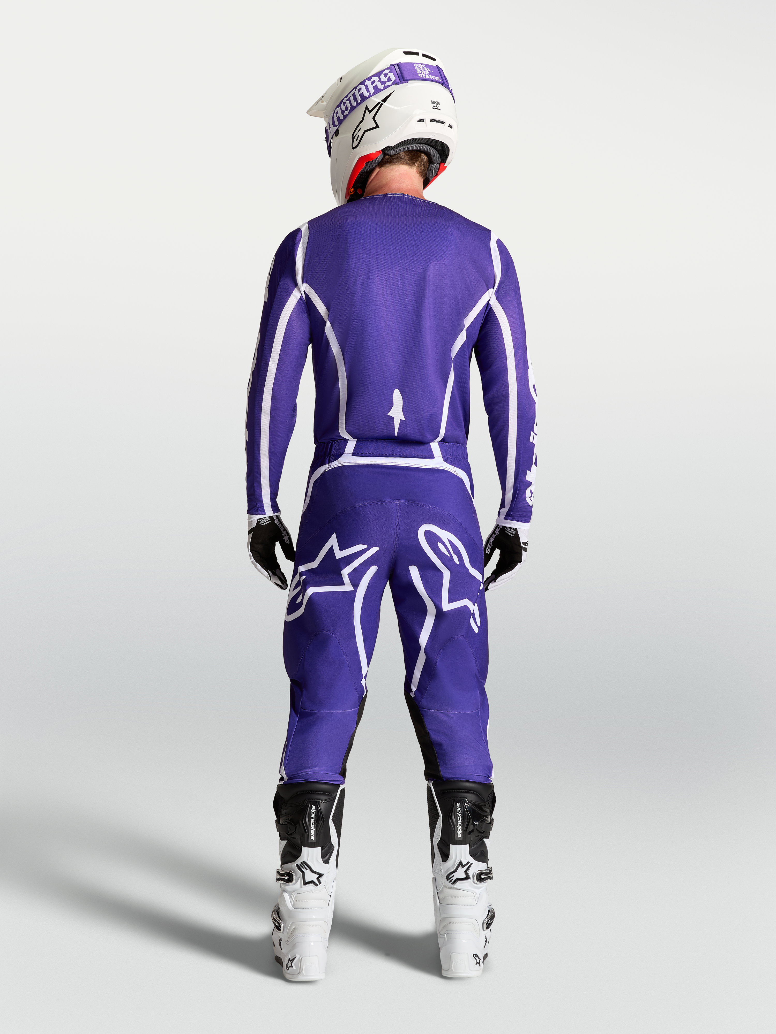 Alpinestars Fluid Apex V2 jersey, blauw en wit, achteraanzicht van motorcrosser met bijpassende broek en witte motorlaarzen.
