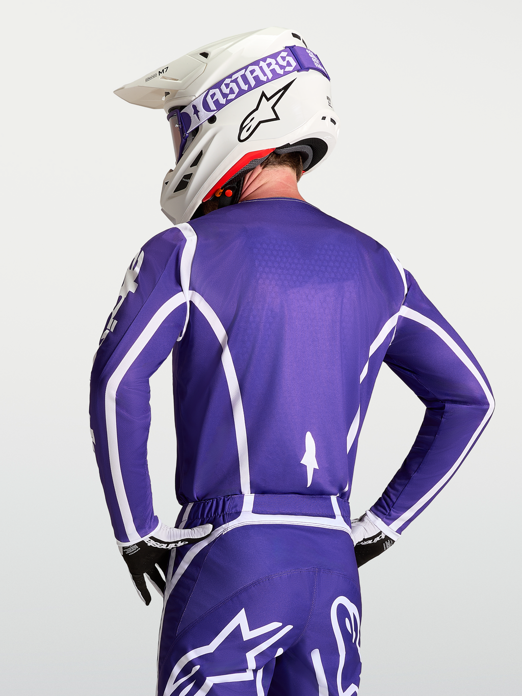 Alpinestars Fluid Apex V2 jersey, heren motorcrossjersey, blauw en wit, ademende polyfabric constructie, getoond vanaf de rugzijde op een model met helm.