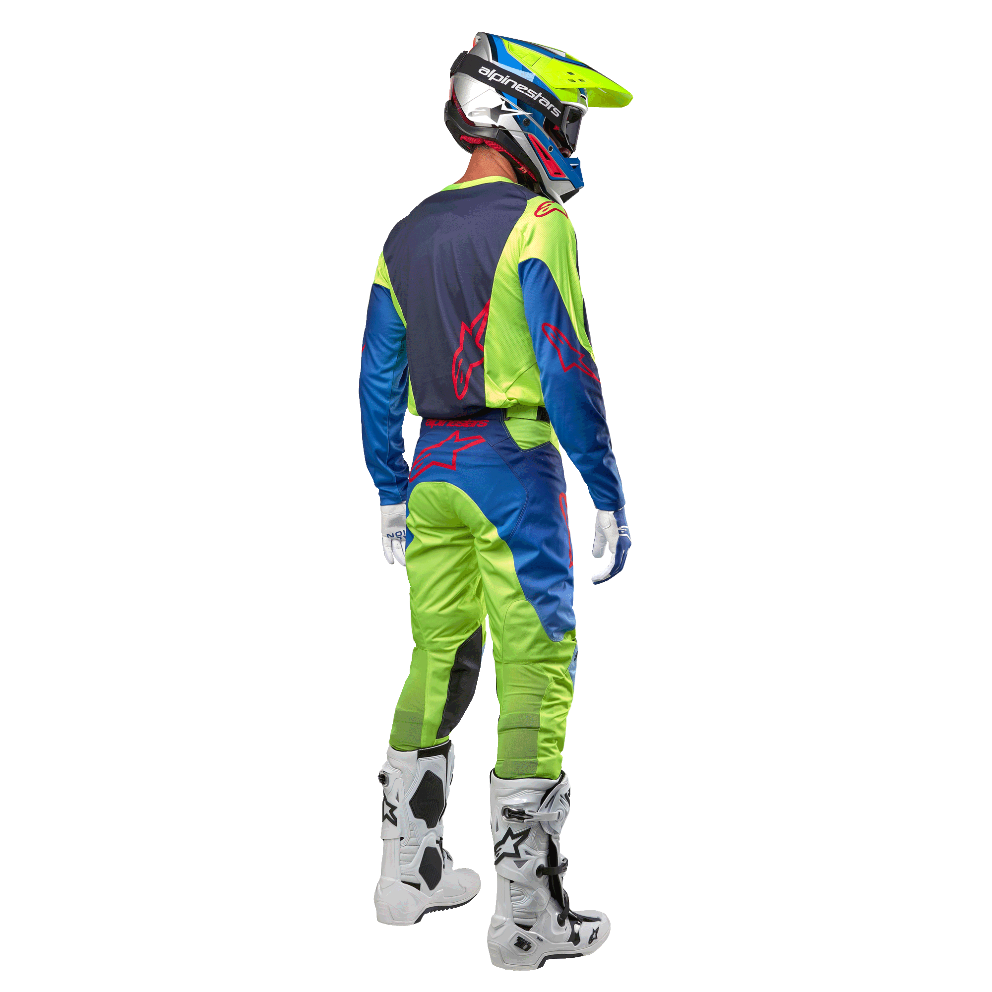 Motocrossrijder van achteren gezien die de Alpinestars 2024 Racer Hoen Jersey draagt in Yellow Fluo en Blue Night Navy, bijpassende motorcrossbroek en witte laarzen, toont het ontwerp aan de achterzijde met rode logo's, gecoördineerde outfit voor professioneel off-road racen