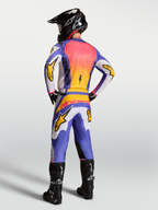 Alpinestars Fluid Drag jersey, lila en blauw met goud, motorcrosser van achteren in volledige MX-uitrusting.