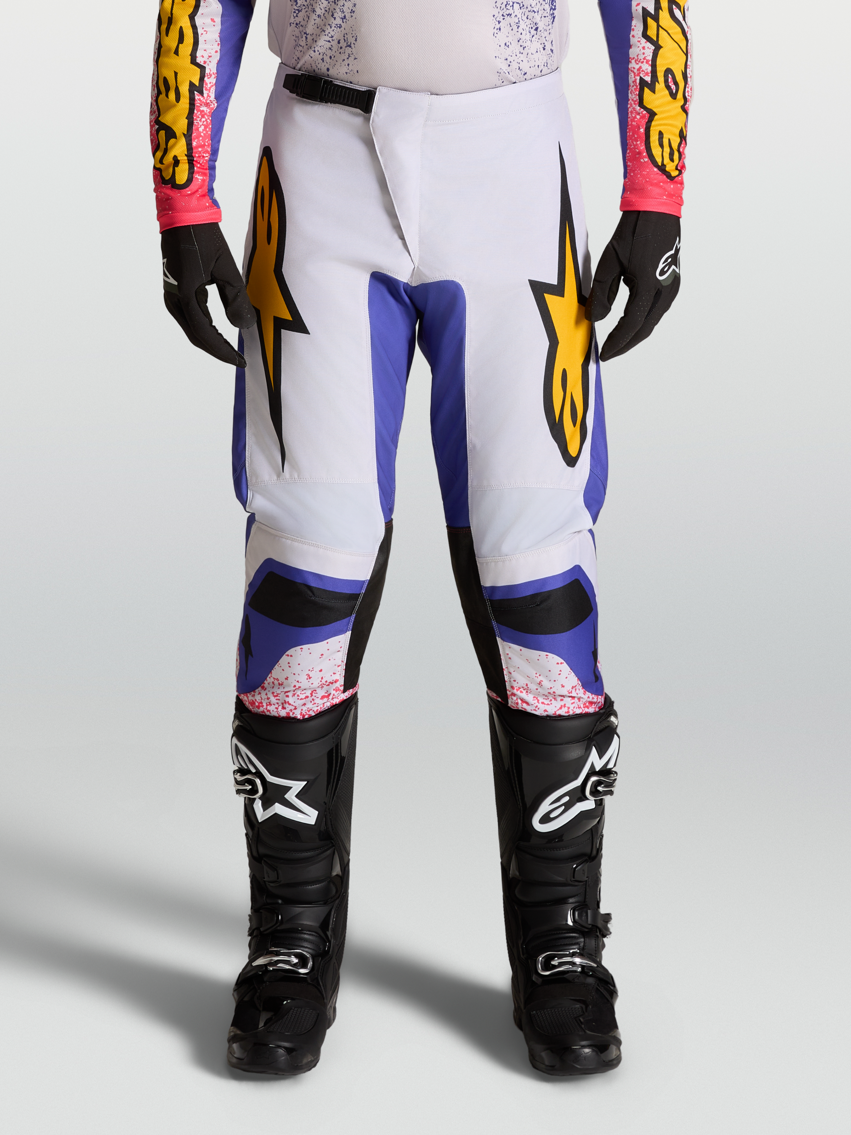 Alpinestars Fluid Drag heren motocrossbroek 2027 in licht lila en iris blauw met gouden accenten.