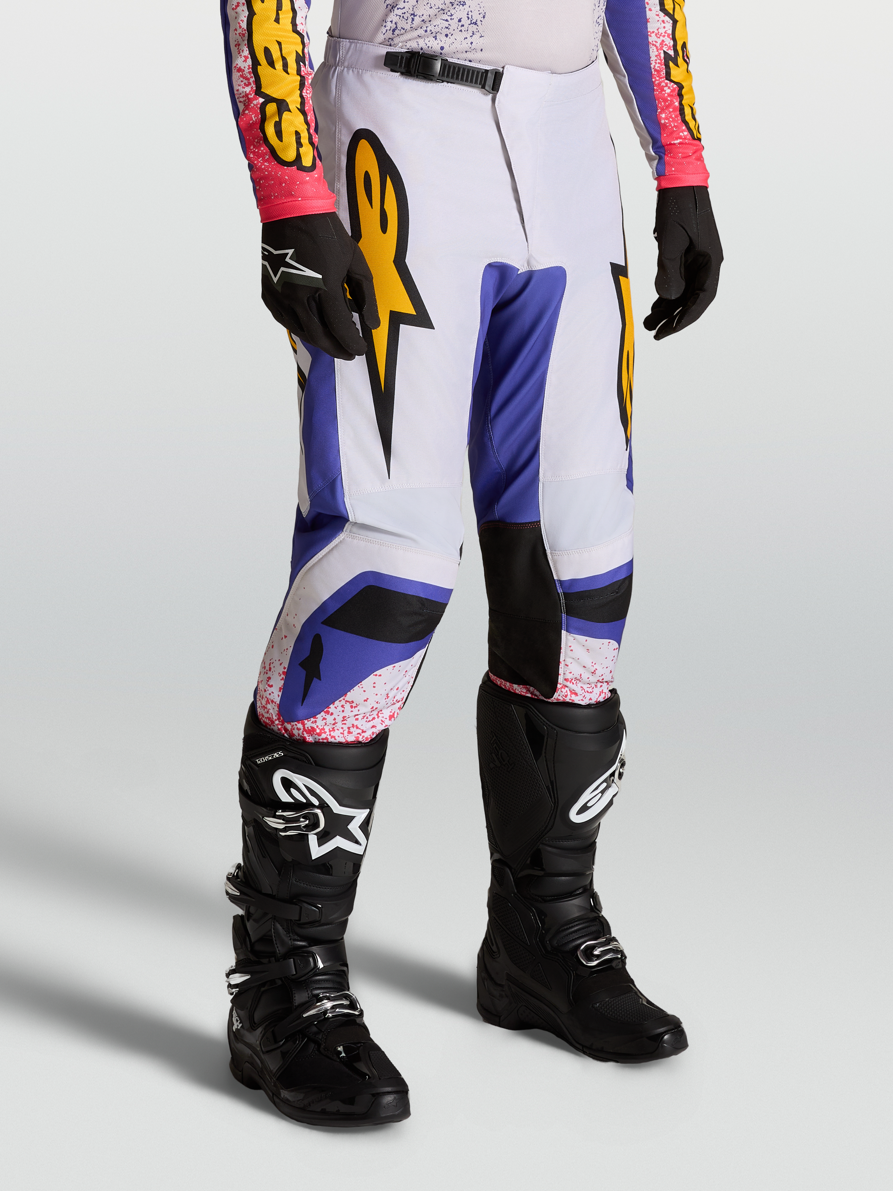 Alpinestars Fluid Drag broek, motorcrossbroek heren, blauw en licht lila met gouden graphics, ergonomische sportieve pasvorm.
