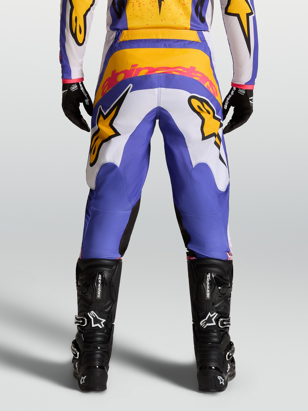 Alpinestars Fluid Drag broek, motorcrossbroek voor heren, blauw en goud, met stretch corduroy en zwarte motorlaarzen.