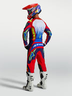 Alpinestars Fluid Drag jersey, blauw en rood motorcross-jersey, heren achteraanzicht met bijpassende gear en witte laarzen.