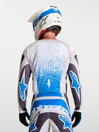 Alpinestars Fluid Drag Jersey, ademende heren-motocrossuitrusting in Graystone en blauw, achteraanzicht van een rijder met SM7 helm en off-road broek.