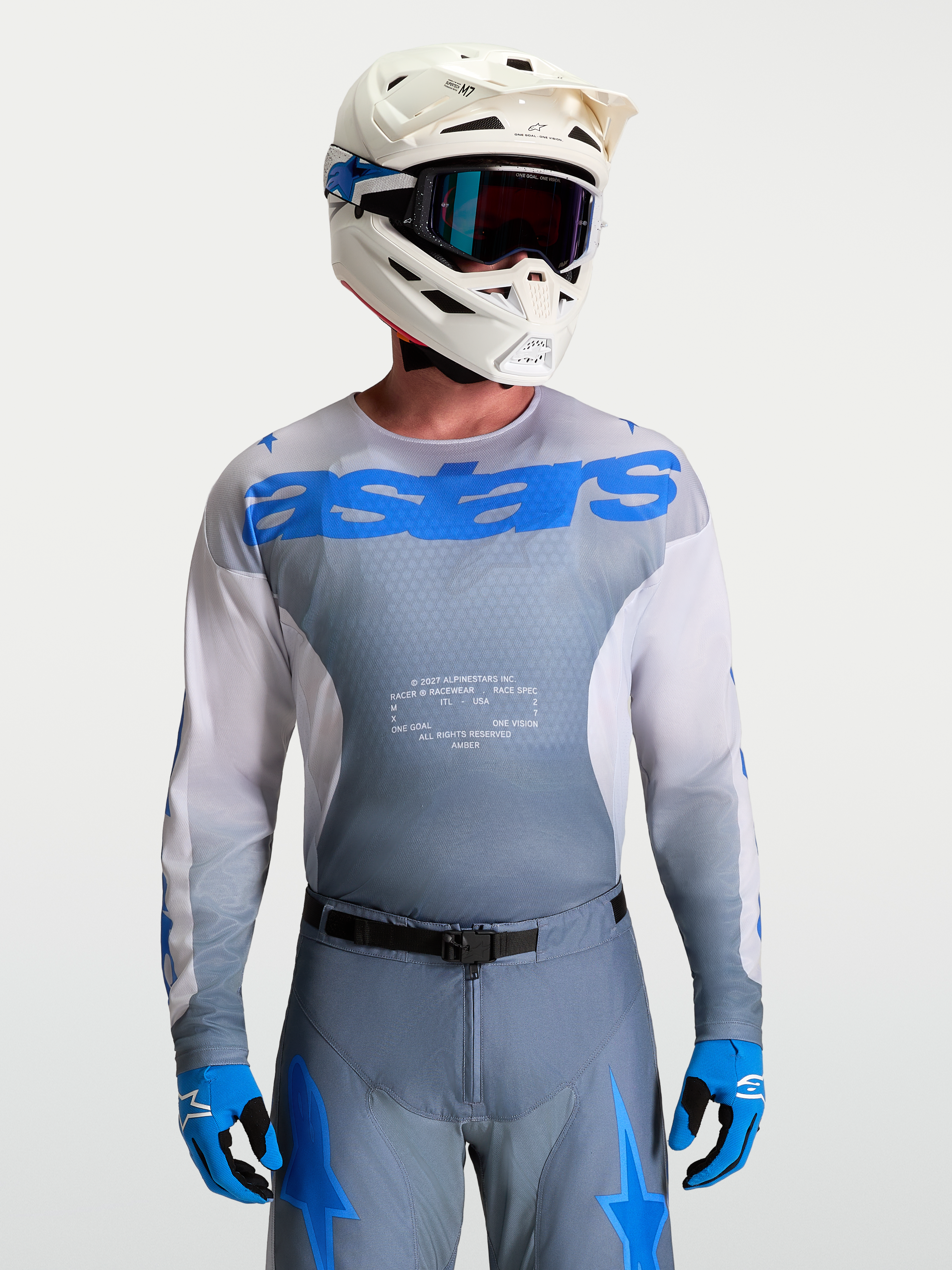 Alpinestars Racer Amber Jersey, Men's Motocross Gear in Gray and UCLA Blue, paired with a white MX helmet and goggles.