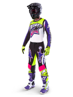 Alpinestars motorcrossrijder in Limited Edition Supertech Dirt Studios® uitrusting, kleurenschema in wit, paars en fluogeel, zwarte broek met opvallende paarse en roze sterlogo's, fluogele handschoenen, paars-witte racelaarzen, zwarte helm, complete professionele racekit voor off-road prestaties