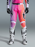 Alpinestars 2026 Racer Air Portl broek, motorcrossbroek, levendig kleurverloop van paars, roze en oranje, met opvallende sterlogo's op de dijen, gedragen met witte racelaarzen en zwarte handschoenen, ontworpen voor high-performance off-road rijden