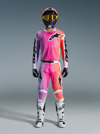 Motorcrosser in volledige Alpinestars 2026 Racer Air Portl race-uitrusting, met een roze, paars en oranje kleurverloop op de broek en jersey, gecombineerd met een bijpassende helm, gele crossbril, witte laarzen en zwarte handschoenen voor een gecoördineerde off-road look