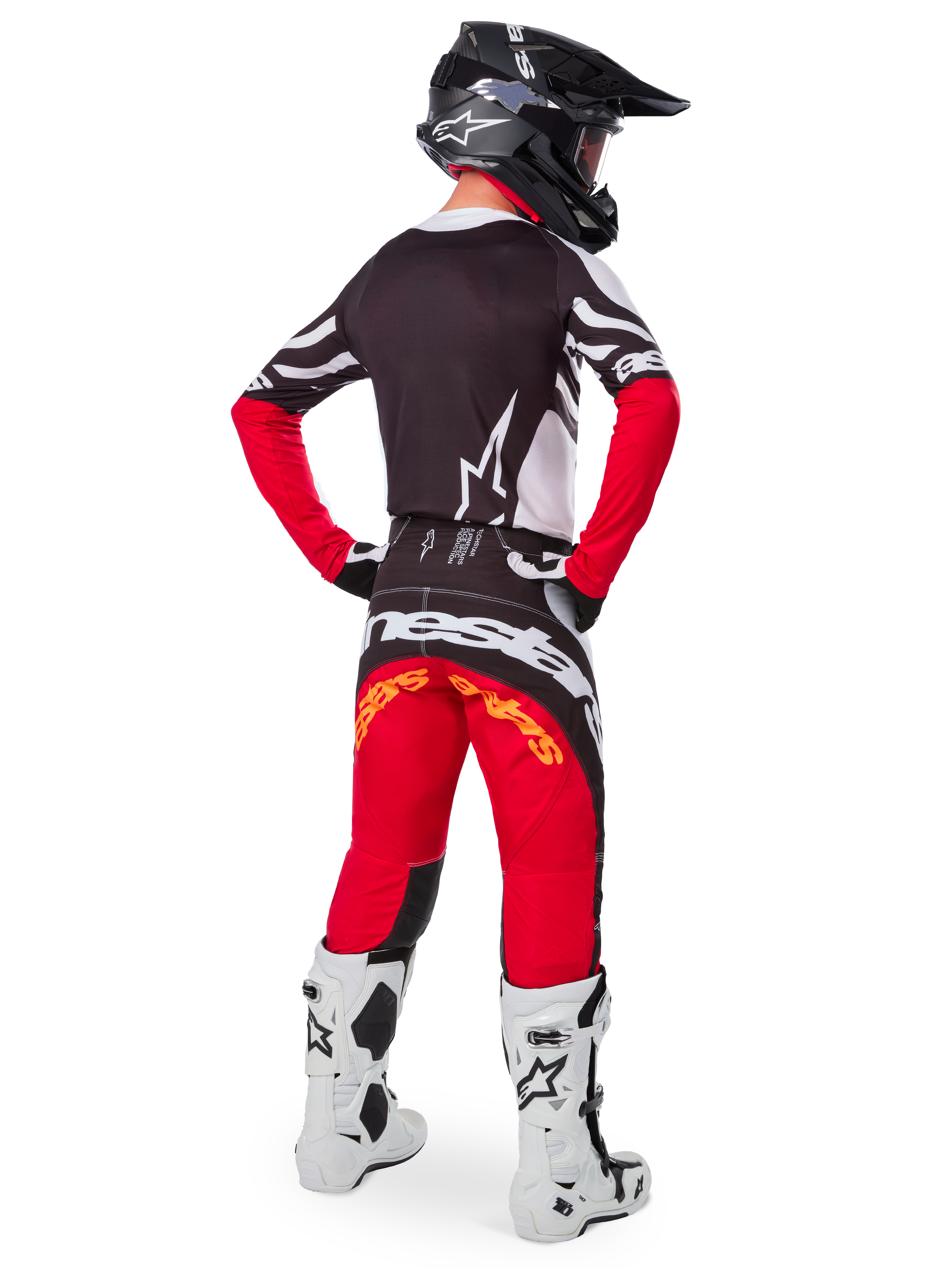Alpinestars Limited Edition Techstar Deep Jersey in Black White High Red, motorcrosser van achteren gezien met een zwart achterpand, wit sterlogo en rode mouwen, gecombineerd met bijpassende rood-zwarte broek, witte laarzen en zwarte helm, complete off-road outfit