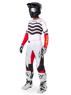 Alpinestars motocrossrijder in volledige race-uitrusting, Limited Edition Techstar Deep Jersey met witte en zwarte gegolfde strepen en rode mouwen, bijpassende wit-rode broek, zwarte helm, wit-zwarte laarzen, gecoördineerde outfit voor off-road racen